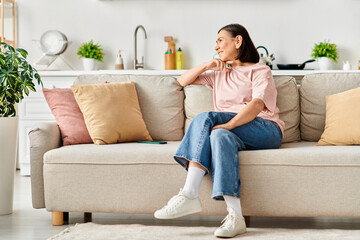 Fototapeta premium A mature, elegant woman dressed in comfortable homewear, sitting on a plush couch in a stylish living room.