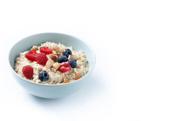 Oatmeal porridge with raspberries, blueberries and almonds in bowl isolated on white background. Copy space