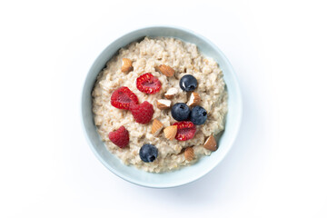 Oatmeal porridge with raspberries, blueberries and almonds in bowl isolated on white background. Top view