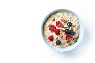 Oatmeal porridge with raspberries, blueberries and almonds in bowl isolated on white background. Top view. Copy space