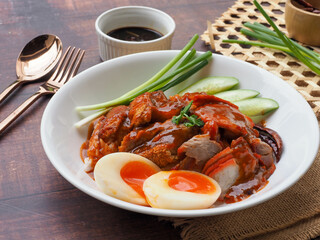 Thai BBQ roast pork , crispy pork and boiled egg over rice topped with red gravy sauce - Thai food called Khao Moo Dang at close up view