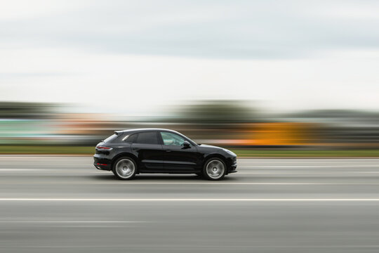 A black car is driving down the street at high speed with a blurred background. Concept of speeding, disobeying traffic rules, dangerous driving