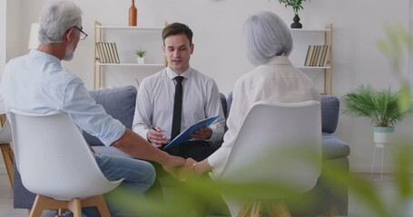 Financial advisor meets with senior couple to discuss investment decisions and future retirement planning.A real estate agent concludes an agreement with a middle-aged couple with gray hair.
