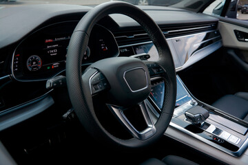 View of the driver's seat of the car through the window. Visible steering wheel, speedometer, gear knob