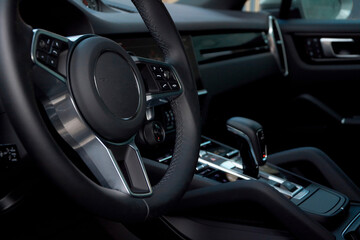 The view of the dark dashboard from the driver's seat is shown, with a close-up of the steering wheel in the foreground. The interior of the car is dark, with metal accents