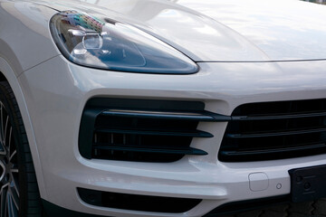 Grey car bumper with black accents, headlight and wheel.
