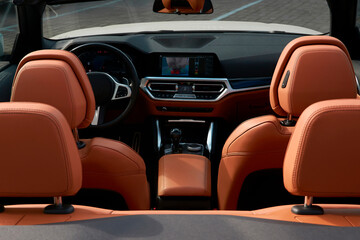 View of the interior of the convertible from the trunk side. You can see the brown backs of the seats and the dashboard.