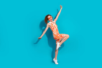 Full size photo of pretty young girl sunglass dance spread hands fly wear trendy orange outfit isolated on aquamarine color background