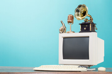 Retro PC monitor, golden microphone, gramophone, arm, keyboard and mouse from circa 1990s on oak...