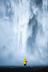 Fototapeta premium Stunning view of the Skógafoss Waterfall with a tourist wearing a yellow jacket. Skógafoss is one of the biggest waterfalls in Iceland, situated on the Skoga River in the south of Iceland.