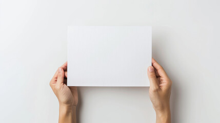 Two hands holding a blank white sheet of paper against a soft, neutral backdrop, poised to deliver an important message or creative idea.