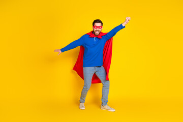 Full size photo of pretty young male flying superman wear trendy blue outfit isolated on yellow...