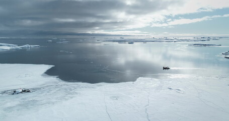 Obraz premium People travel Antarctica shore ride zodiac boat. Frozen polar ocean ice coast. Arctic snow covered landscape. Explore South Pole wild winter nature. Tourism, travel, expedition. Aerial drone panorama
