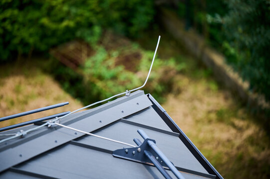 Lightning rod and snow guards on building's roof. Lightning rod is metal rod intended to protect from lightning strikes. Snow guards hold snow on roof, preventing it from sliding off suddenly.