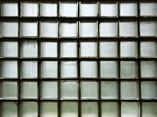 A window made of green glass blocks in a dark room