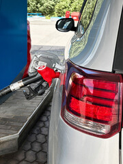 Refueling a silver car with a red gasoline pump with 92 octane at a gas station