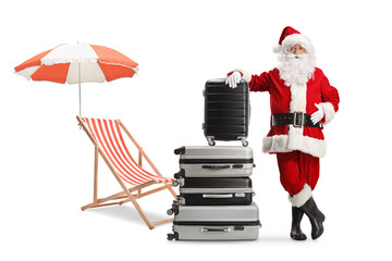 Santa claus with a pile of suitcases next to a beach chair and umbrella