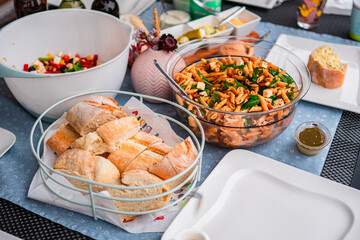 Fresh Noodle Salad and Warm Loaf Bread Slices in Bowls on a Table as Side Dish for Grill Season on...
