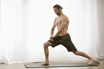 Fototapeta premium At-home yoga practice a man, handsome and focused, balances gracefully on a mat.