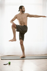 Fototapeta premium Handsome man practices yoga on a mat at home.
