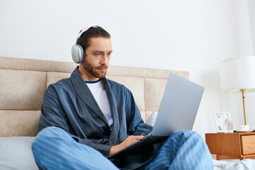 A man meditating on a bed, browsing the web on a laptop.