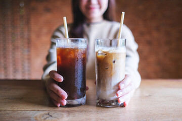Closeup image of a young woman holding and serving two glasses of iced coffee