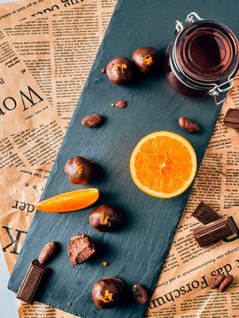 Chocolate truffels with oranges with orange slices and cocoa beans on a slate board