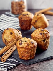 Close-up of a freshly banana vegan chocolate chip cupcake on a slate board with cinnamon sticks