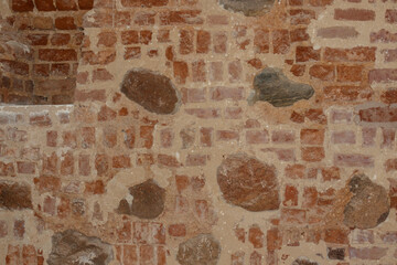 The wall is made of old red brick and stones. Brick background.