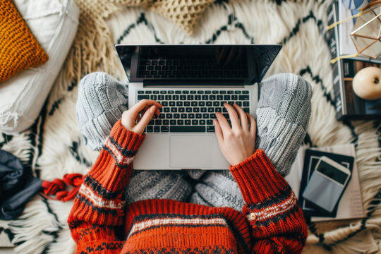 Woman wearing a red sweater is typing on a laptop while working from home in a cozy atmosphere - Powered by Adobe