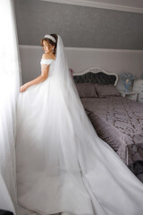 Fototapeta premium A bride is standing in front of a bed with a white dress and a veil. The image has a romantic and elegant mood