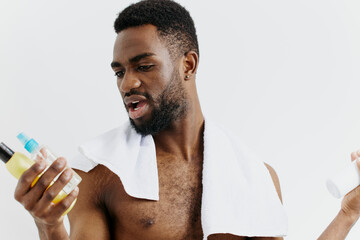 Shirtless man with lotion and shampoo promoting skincare and haircare products in a wellness and grooming concept