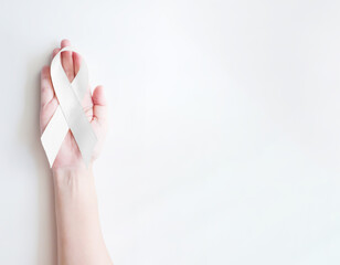Hand hold White light pearl color ribbon for Lung cancer awareness and Multiple Sclerosis, symbol for international day of non-violence, cancer disease treatment of disease control