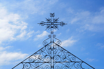 Cruz de hierro forjado y adornos sobre cielo azul