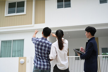 Final Home Inspection, A couple inspects the exterior of new home, pointing out details, while an...