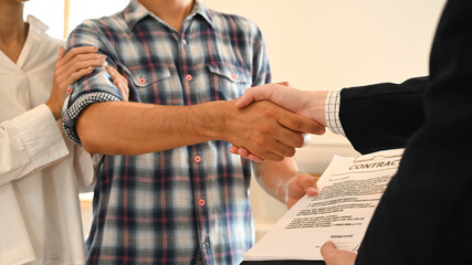 A Crop shot of a handshake between a couple and their real estate agent signifies the successful...