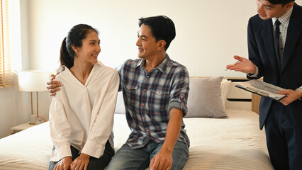 A couple enjoys a warm moment in their new bedroom while discussing final details with their real estate agent