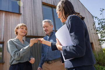 Real estate agent giving keys to a happy mature couple
