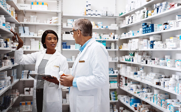 Medical, people and conversation with tablet in pharmacy for inventory, update and prescription. Healthcare, intern and pharmaceutical student with mentor by pills for dispensary, training or support