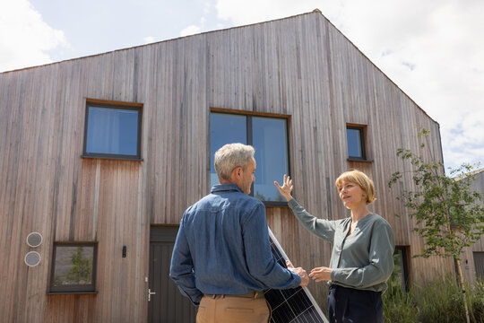 Eco conscious home owner discussing with an engineer installing solar panels