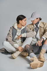 Fototapeta premium A man and a woman, dressed stylishly, are seated together on the ground in a serene moment of intimacy and connection.