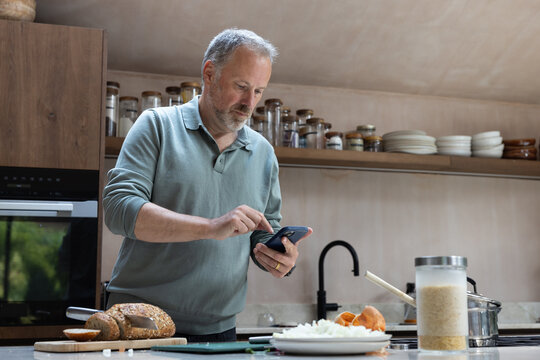Mature retired male checking recipe online whilst he prepares a homemade meal