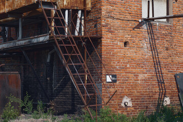 Red brick industrial building close up. Rust of stairs and metal structures and erosion of bricks....