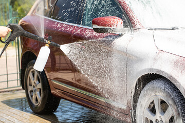 Naklejka premium Cleaning car using active foam. Man washing his car