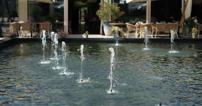 city fountain with urban cafe and restaurant on the background. Weekend evening and holidays concept. High quality 4k footage
