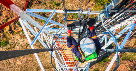Aerial view, technician climbing on a communication tower to repair an cellular antenna for wireless internet
