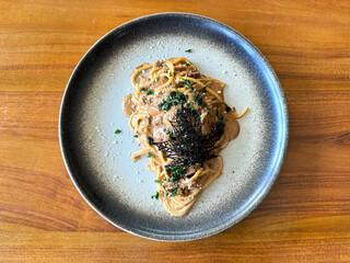 Pasta spaghetti chicken mushroom stroganoff, with seasoned seaweed and Italian herbs, served on natural stone terrazzo table.