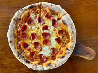 Pepperoni pizza with mozzarella cheese and mushroom, served with Italian herbs, on a pizza pan, on top of wooden table. - Powered by Adobe