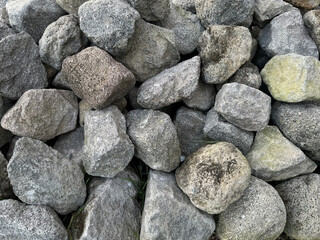 Natural river bedrock, exposed cobblestone and grunge in random slab cut, stacked into stone wall beside riverbanks, foundation, or solid wall gabion.