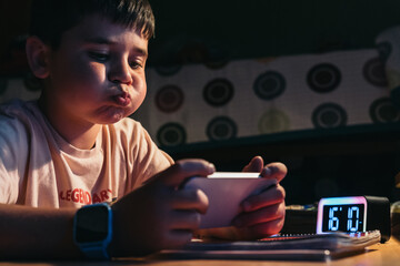 Young boy playing on smartphone instead of doing homework. Young boy is snorting on playing a game...